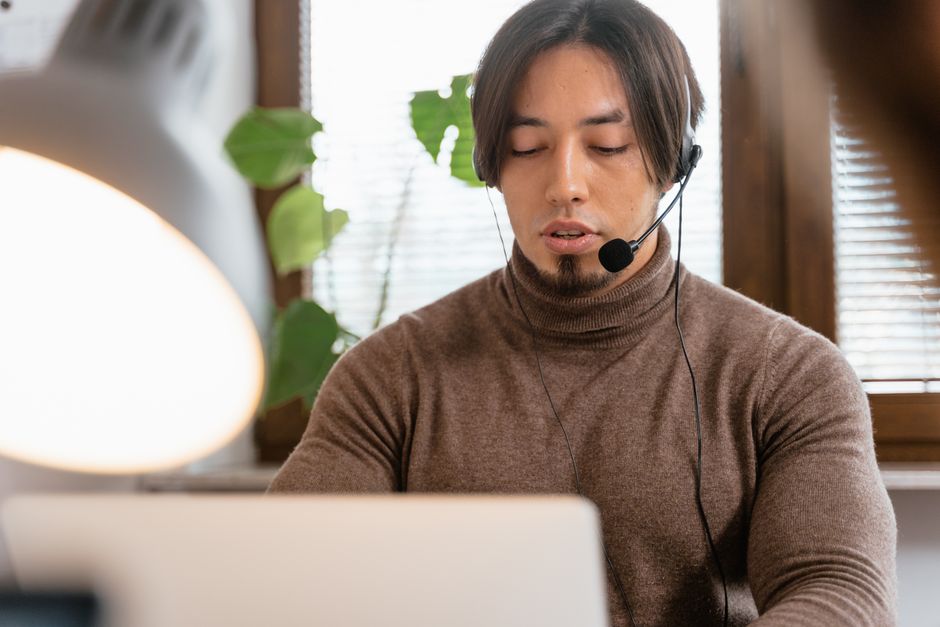 Operador de call center com headset trabalhando em home office, focado em atendimento ao cliente.