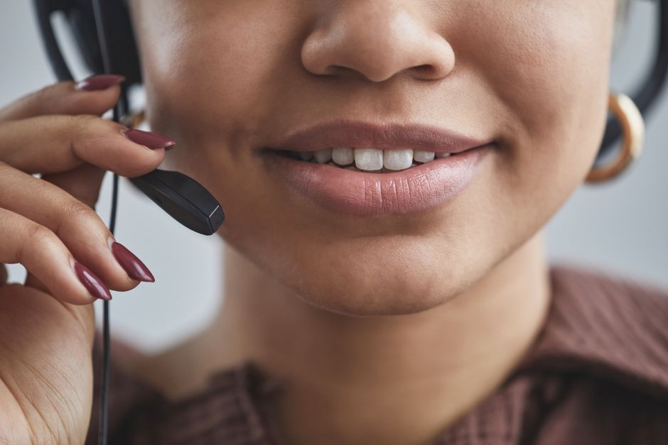 Close-up amigável de uma mulher com um fone de ouvido em um call center, mostrando um comportamento profissional.