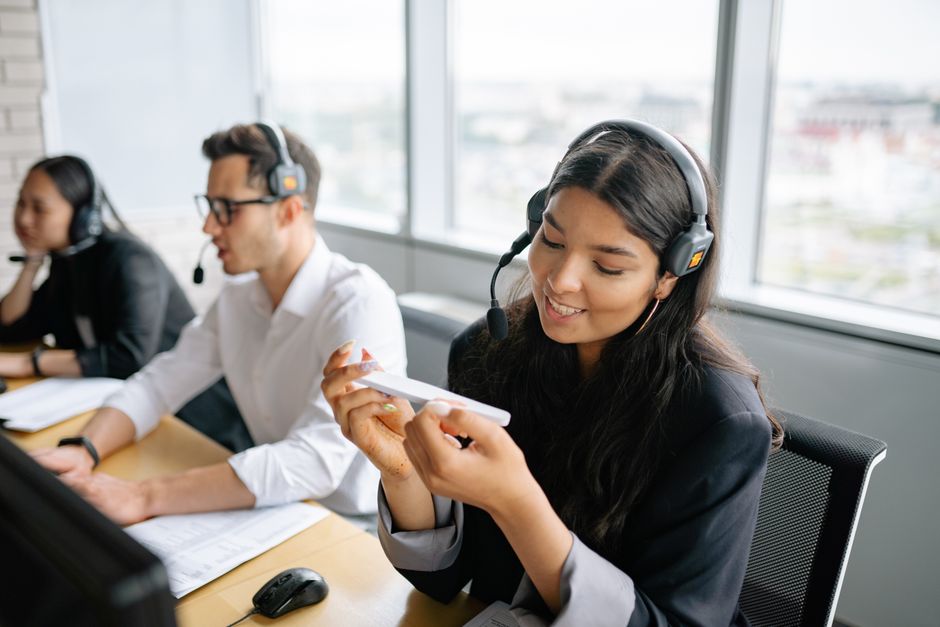 Agentes de call center diversos trabalhando de forma colaborativa em um ambiente de escritório iluminado.