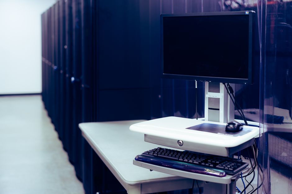 Um data center moderno com uma configuração de computador com monitor e teclado, enfatizando a infraestrutura tecnológica.