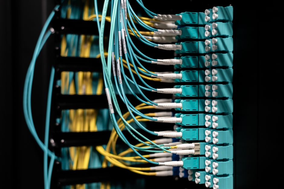 Vista de perto de cabos de fibra óptica organizados e arrumados em uma patch panel para gestão de dados eficiente.