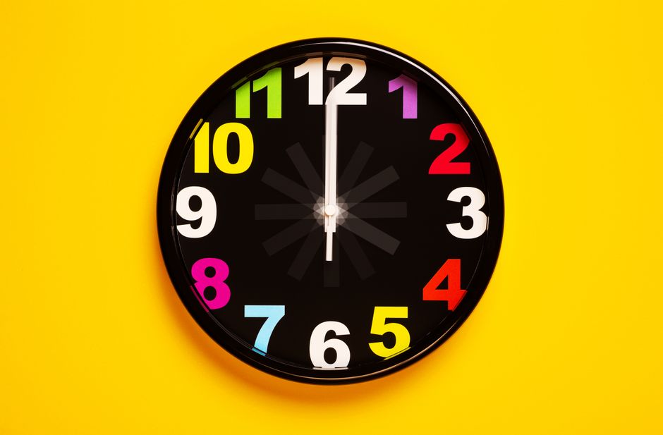 Relógio de parede vibrante com números coloridos sobre um fundo amarelo brilhante, enfatizando a decoração moderna.