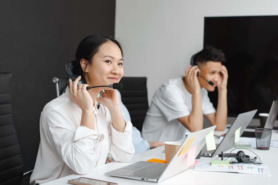 Um grupo diversificado de atendentes de call center trabalhando com laptops e fones de ouvido em um escritório moderno.