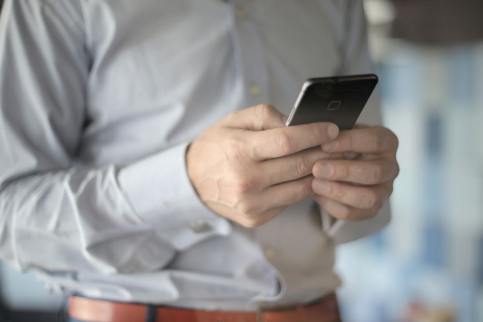 Close-up de um empresário usando um smartphone, destacando temas de negócios e comunicação.
