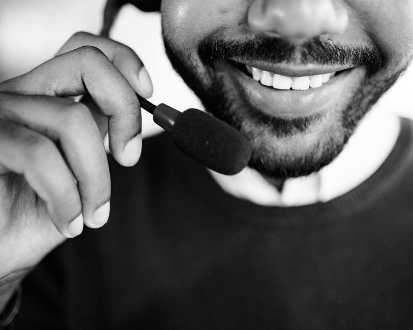 Close-up de um agente de call center sorridente segurando um microfone de headset.